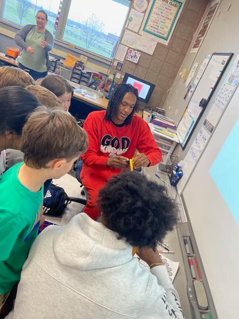 Senior Jeremiah Godfrey takes a few moments to teach a new game to elementary students as the reading program wrapped up for the day. 