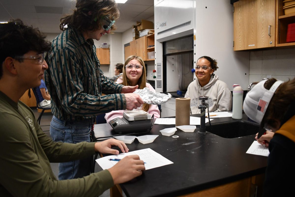 Science teacher Ryan Blood helps a group of his students with an experiment during class. 